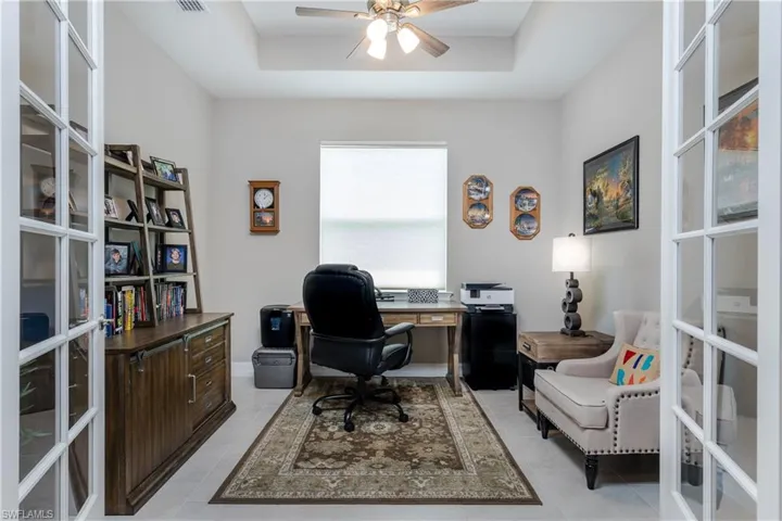 Home office with ceiling fan, a raised ceiling, and light tile patterned floors