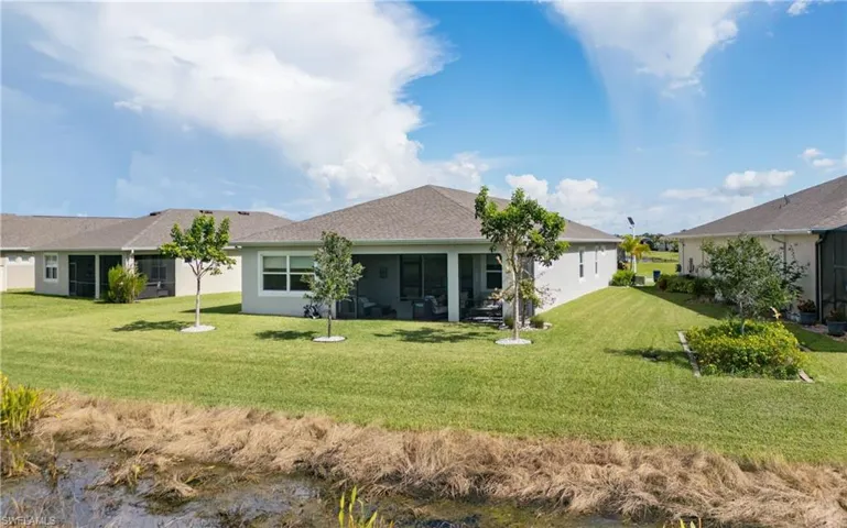 Back of property featuring a lawn, a sunroom, a water view, and roof with shingles