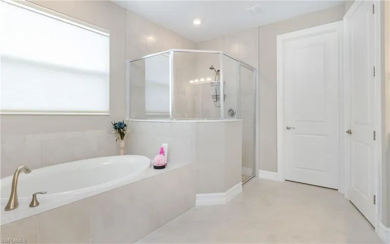 Bathroom with a garden tub, a stall shower, and tile patterned flooring