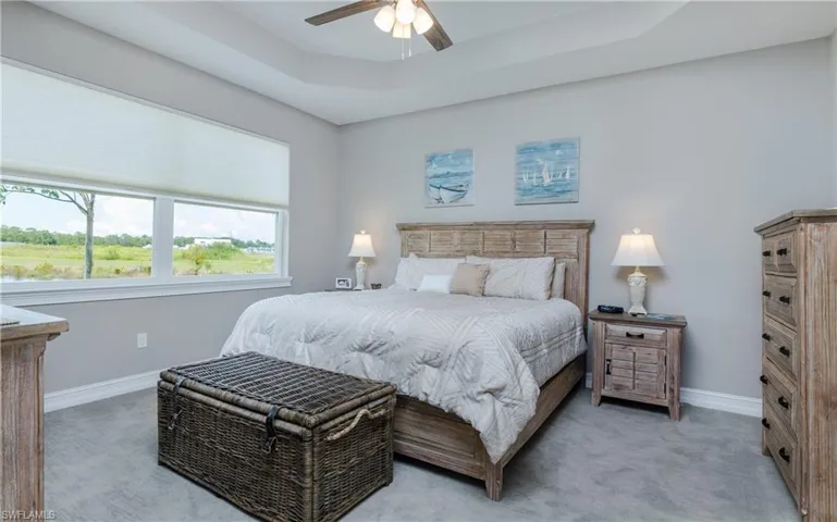 Bedroom with a tray ceiling, ceiling fan, and light colored carpet