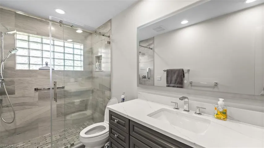 Guest bathroom featuring a frameless glass shower enclosure with a rain shower head and handheld sprayer