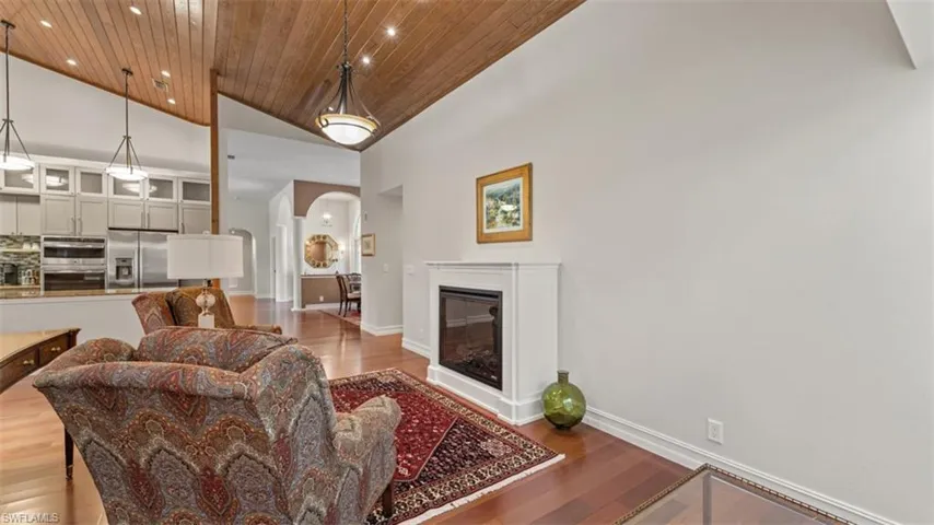 Living area featuring a vaulted wood-paneled ceiling, a built-in fireplace with a white mantel, and wood-finish flooring