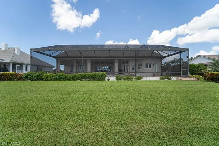 Expansive rear exterior featuring a screened-in lanai, covered patio space, and a manicured lawn