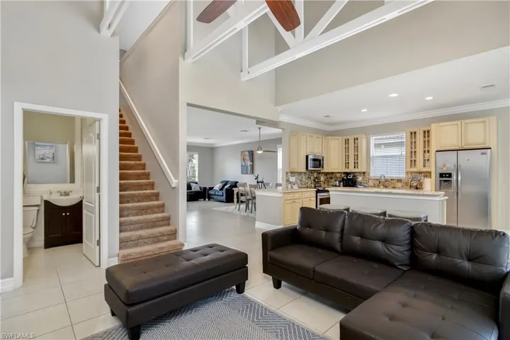 Tiled living room featuring a towering ceiling, plenty of natural light, sink, and ceiling fan