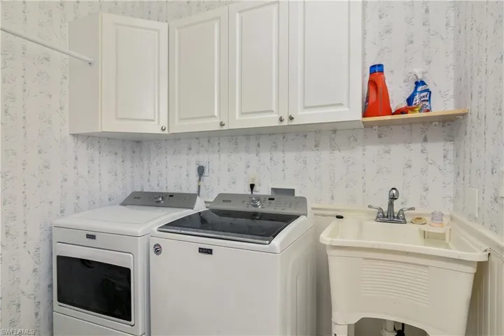Clothes washing area featuring washer and dryer, cabinets, hookup for an electric dryer, hookup for a washing machine, and sink