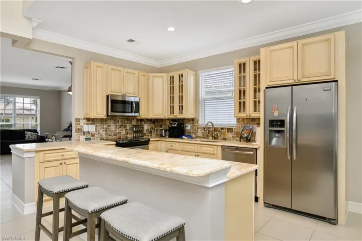 Kitchen featuring appliances with stainless steel finishes, backsplash, kitchen peninsula, and light tile floors