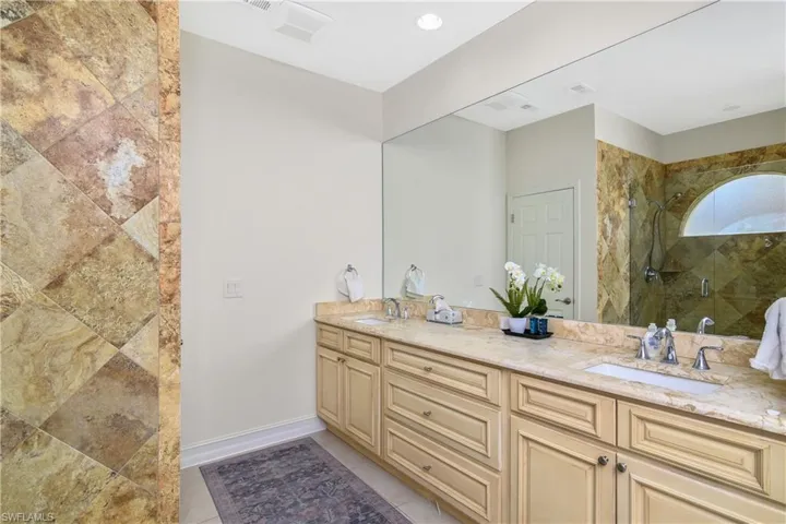 Bathroom featuring tile floors, a tile shower, and dual bowl vanity