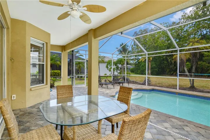 View of pool featuring a patio, glass enclosure, and ceiling fan