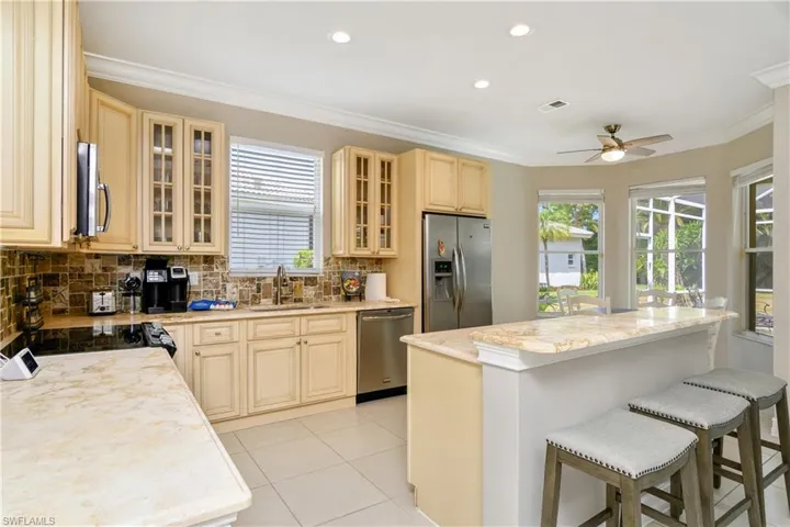 Kitchen featuring ceiling fan, tasteful backsplash, a kitchen island, sink, and appliances with stainless steel finishes