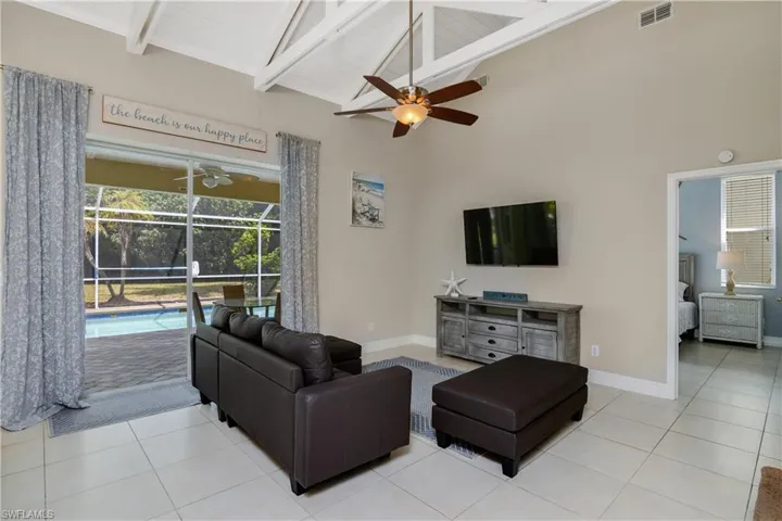Tiled living room with beam ceiling, high vaulted ceiling, and ceiling fan