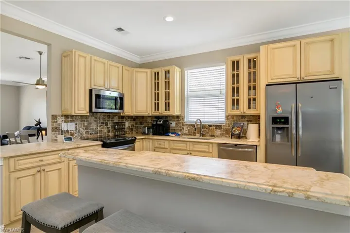 Kitchen with appliances with stainless steel finishes, kitchen peninsula, sink, tasteful backsplash, and a kitchen bar