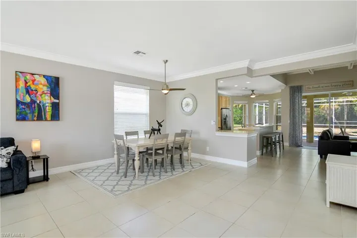 Dining room with ceiling fan, crown molding, and light tile floors