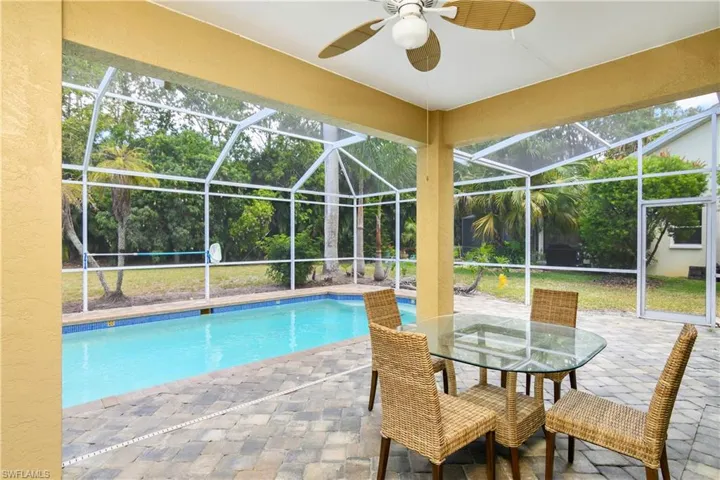View of swimming pool featuring ceiling fan, glass enclosure, and a patio area