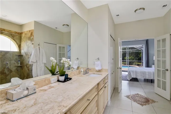 Bathroom with tiled shower, plenty of natural light, vanity, and french doors