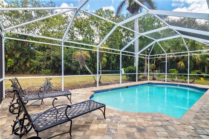 View of swimming pool with glass enclosure and a patio area