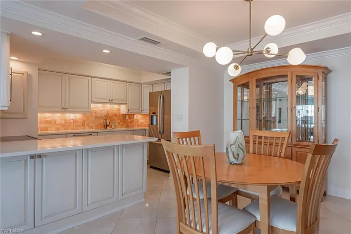 Dining area featuring light tile patterned flooring, crown molding, recessed lighting, and a chandelier