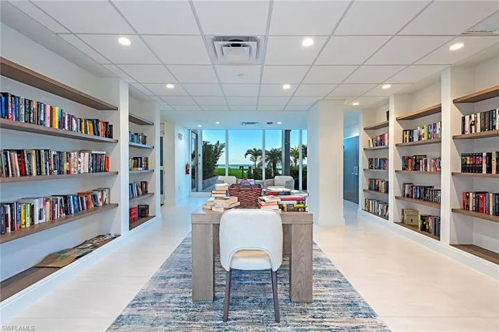 Living area with wall of books, recessed lighting, a paneled ceiling, and expansive windows