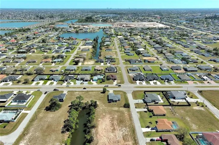 Aerial view of property and surrounding area featuring a nearby body of water and nearby suburban area