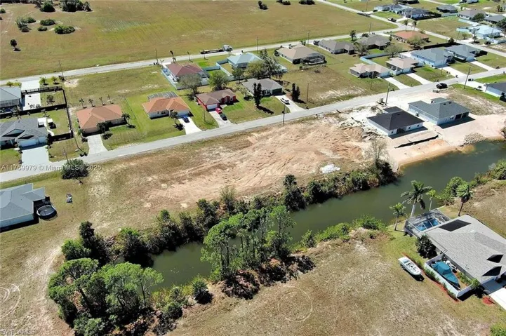 Aerial view of property and surrounding area featuring a nearby body of water and nearby suburban area