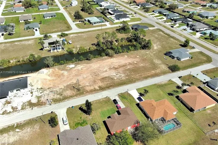Aerial view of property and surrounding area featuring nearby suburban area and a large body of water
