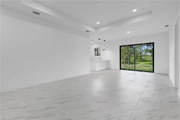 Unfurnished living room featuring a tray ceiling, light marble finish floors, and recessed lighting