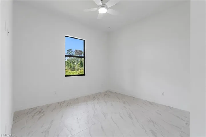 Spare room with light marble finish floors and a ceiling fan