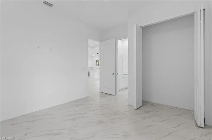 Unfurnished bedroom with light marble finish floors and a closet
