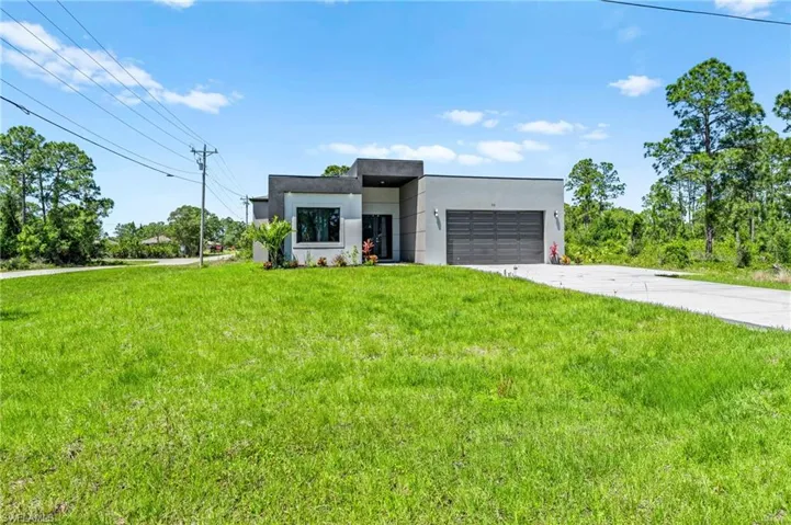Contemporary house featuring stucco siding, driveway, a front lawn, and a garage