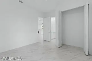 Unfurnished bedroom with light marble finish floors and a closet