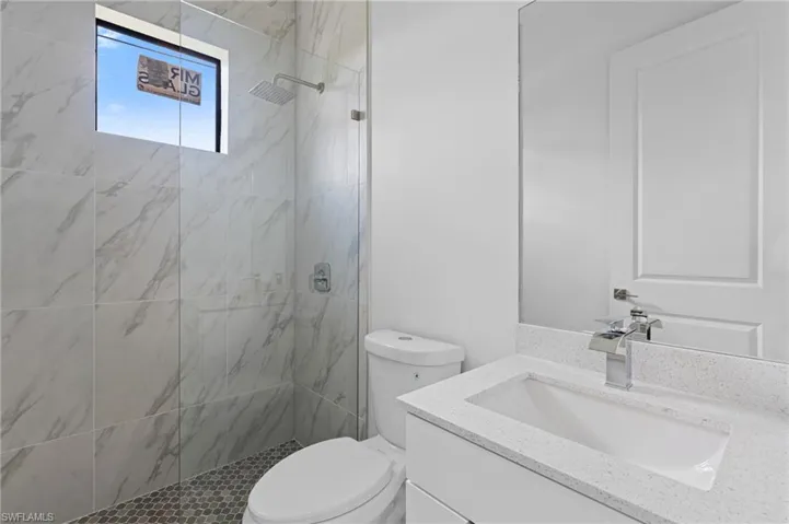 Full bath featuring a marble finish shower and vanity