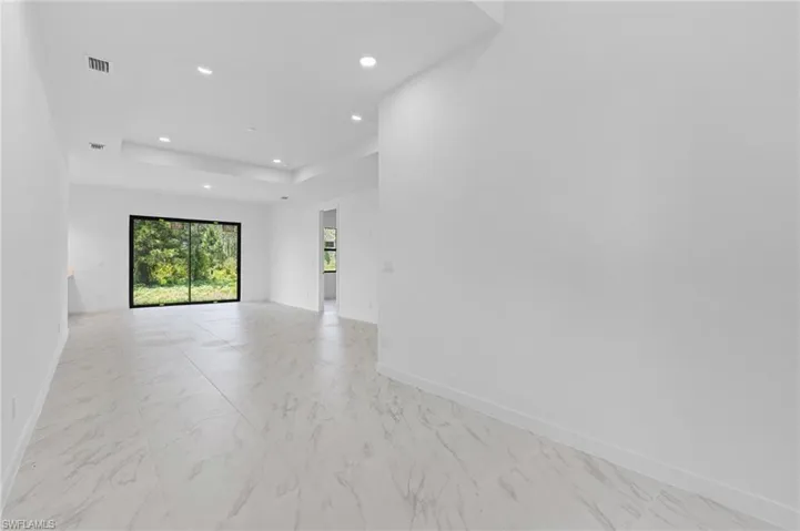 Spare room featuring light marble finish floors, recessed lighting, and a tray ceiling