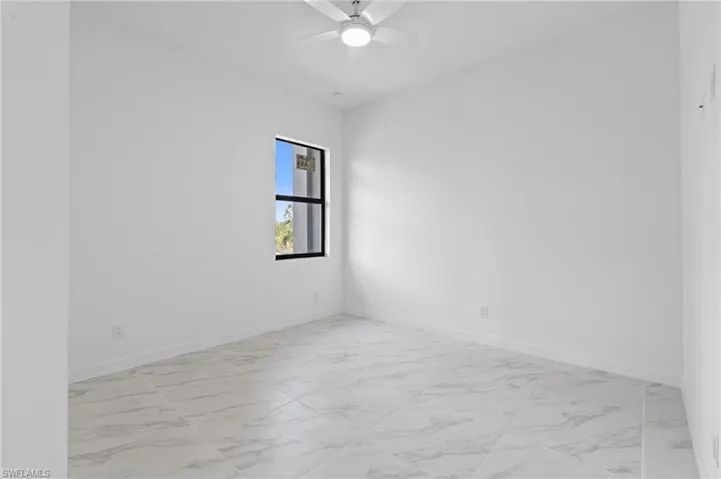 Empty room featuring light marble finish flooring and ceiling fan