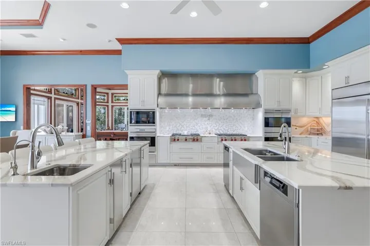 Kitchen with a kitchen island with sink, ornamental molding, light stone counters, tasteful backsplash, and recessed lighting