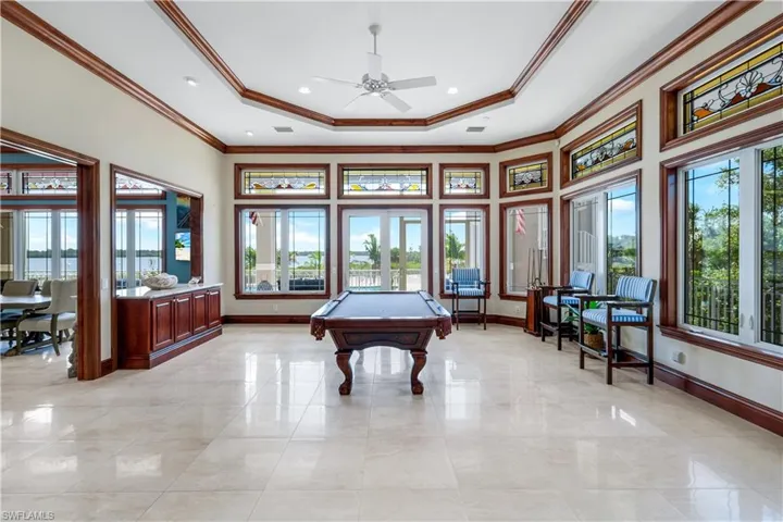 Rec room featuring pool table, crown molding, a tray ceiling, plenty of natural light, and a high ceiling