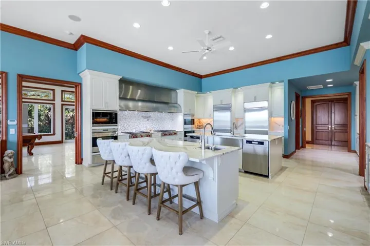 Kitchen featuring crown molding, decorative backsplash, a kitchen breakfast bar, white cabinets, and recessed lighting