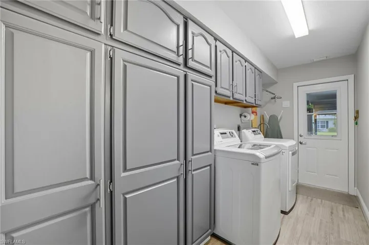 Laundry room featuring light wood-style floors, independent washer and dryer, and cabinet space
