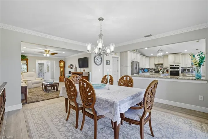 Dining space with crown molding, light wood-style flooring, ceiling fan, a chandelier, and recessed lighting