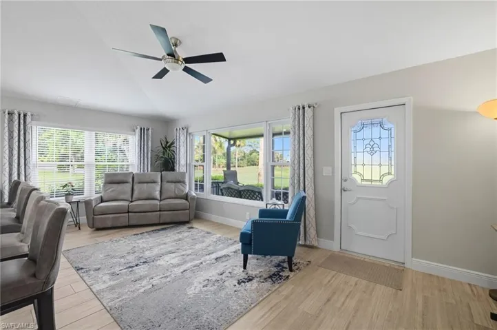 Living area with vaulted ceiling, light wood-style flooring, and ceiling fan