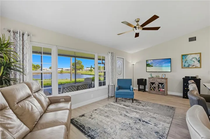 Living area with vaulted ceiling, light wood-style flooring, and ceiling fan