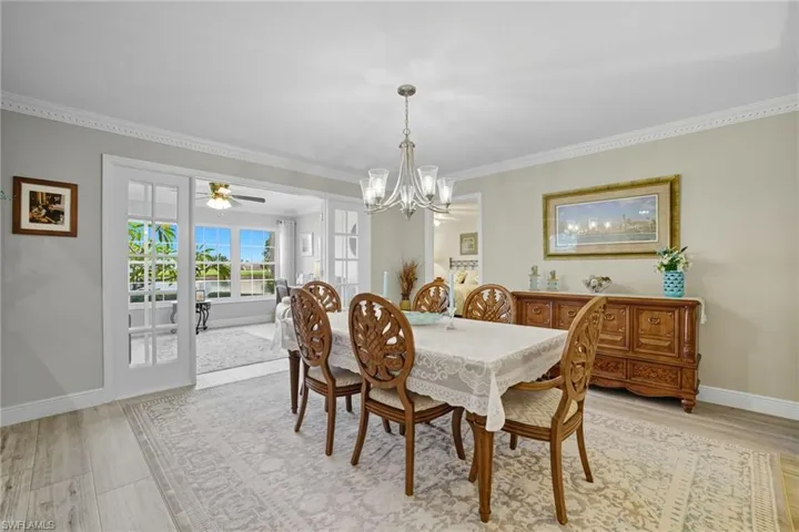 Dining space featuring light wood-style flooring, ornamental molding, a chandelier, and ceiling fan