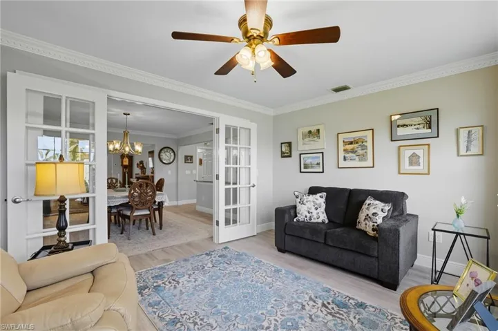 Living area with crown molding, wood finished floors, a ceiling fan, and a chandelier