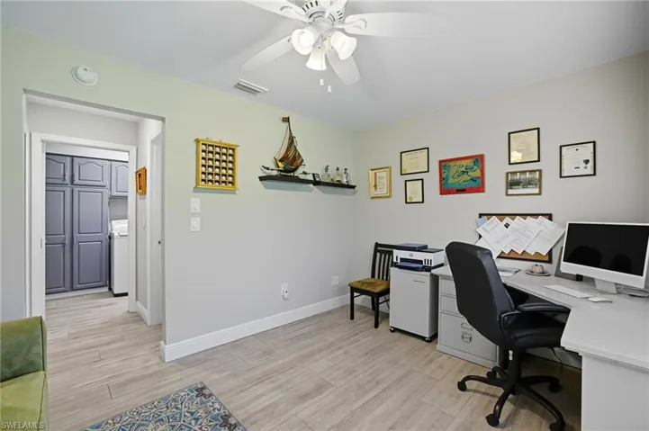 Home office featuring a ceiling fan, light wood-style flooring, and washer / dryer