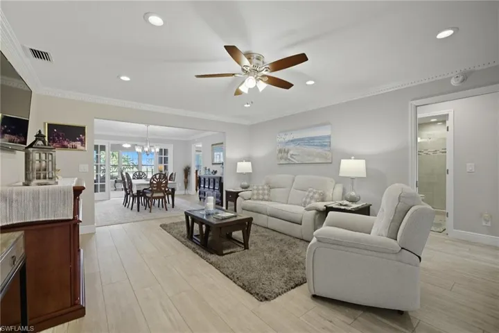 Living area featuring light wood-type flooring, ceiling fan, ornamental molding, recessed lighting, and a chandelier
