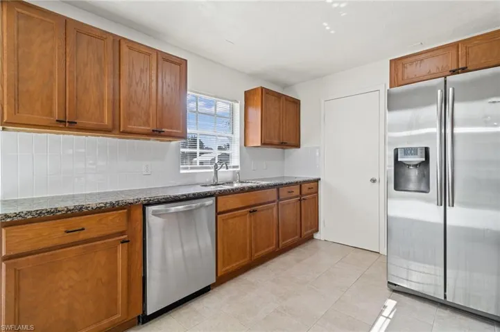 Kitchen featuring stainless steel appliances, brown cabinets, and dark stone counters