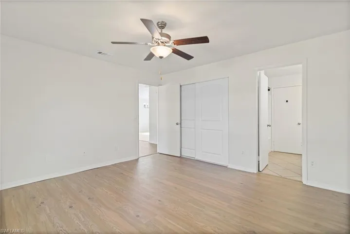 Unfurnished bedroom featuring light wood-style flooring, ceiling fan, and a closet