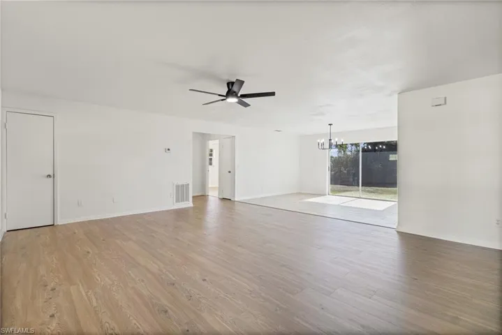 Unfurnished living room featuring a chandelier, a ceiling fan, and light wood-style floors