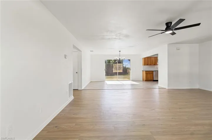 Unfurnished living room with a chandelier, light wood finished floors, and a ceiling fan