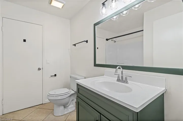 Full bath with vanity, light tile patterned floors, and a shower