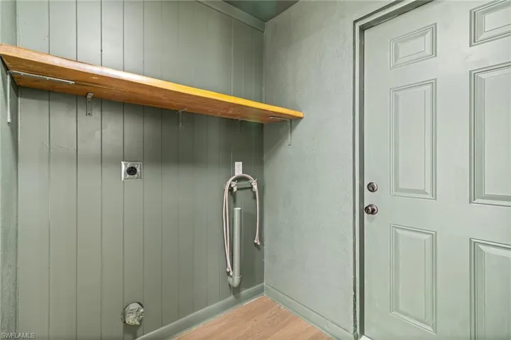 Laundry room featuring light wood-style flooring, a textured wall, electric dryer hookup, and wooden walls