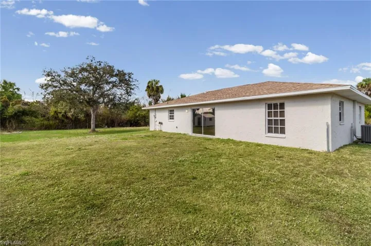 Back of house featuring a lawn and stucco siding